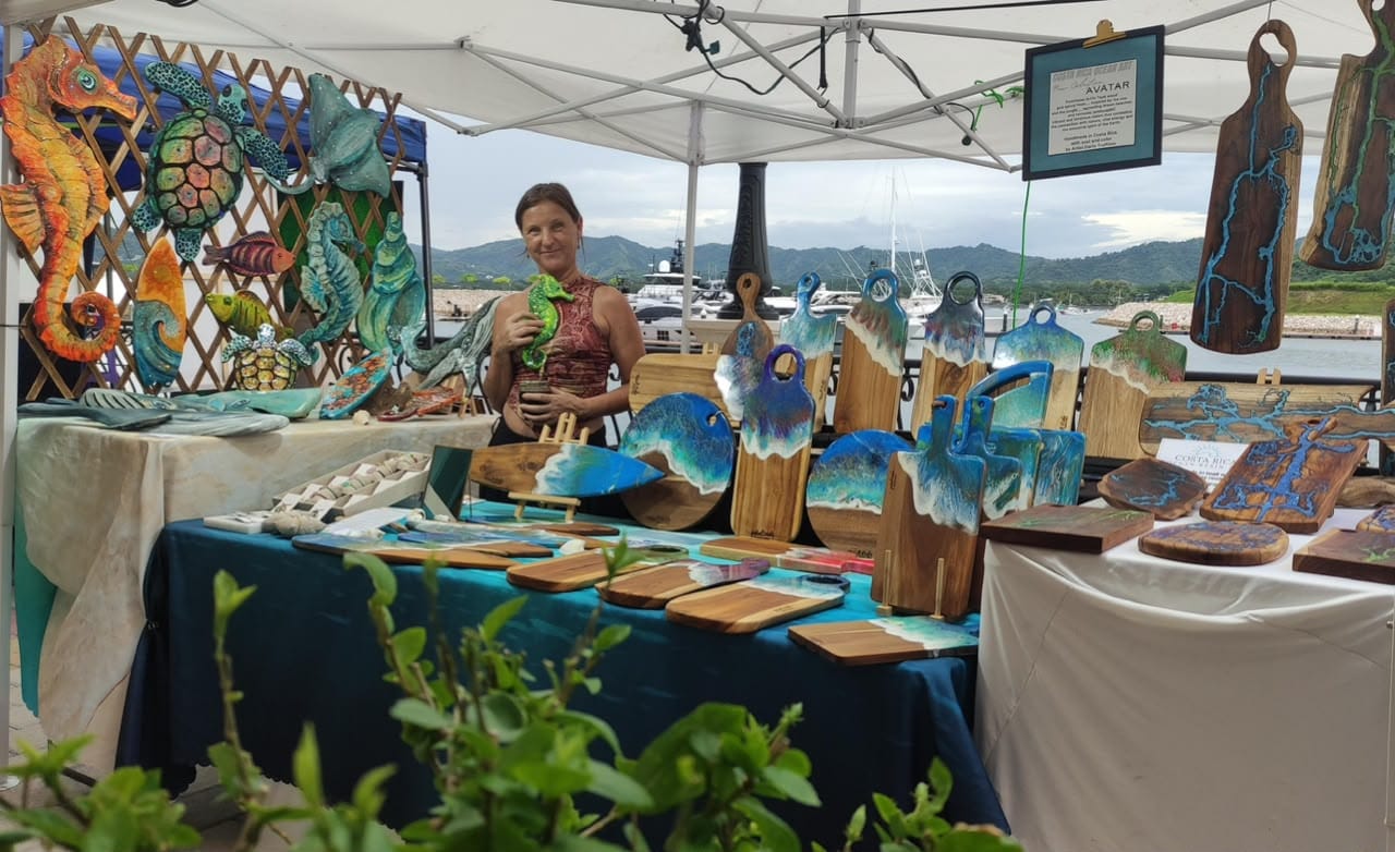 Artista en el stand de BLISS con tablas de resina en un mercado junto a la marina